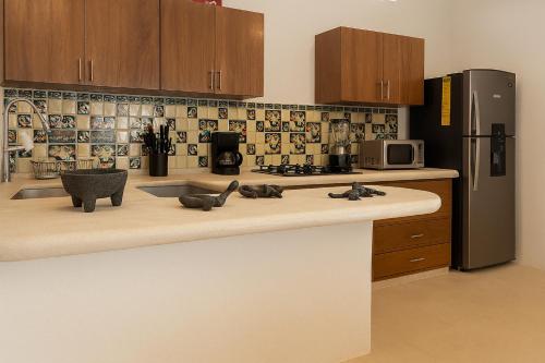 a kitchen with a counter top with a refrigerator at Casa Maya, tu escape con alberca privada in Puerto Escondido