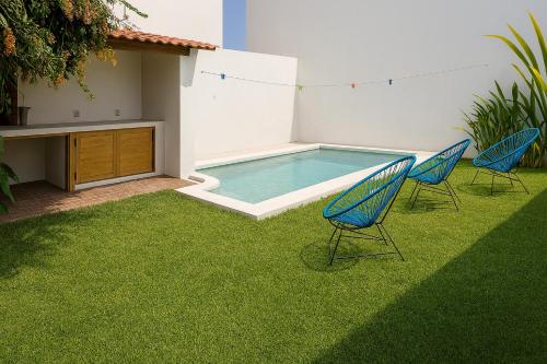 a yard with two chairs and a swimming pool at Casa Maya, tu escape con alberca privada in Puerto Escondido