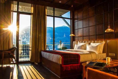 a bedroom with a bed and a large window at Hamta 270 Cliff Resort - 270 Degree Mountain View Suites, Sethan Manali in Manāli