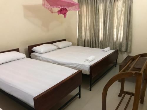 two beds in a room with a chair and a window at Wild Wild Holiday in Kataragama