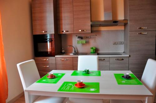 uma cozinha com uma mesa branca com placemats verdes em Morsenchio Flat em Milão