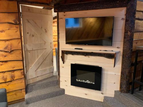 a living room with a fireplace and a tv and a door at The Treehouse at 11 Gables - Center of Ludlow Village near Shopping and Restaurants in Ludlow