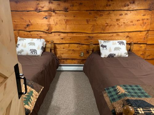 two beds in a room with wooden walls at The Treehouse at 11 Gables - Center of Ludlow Village near Shopping and Restaurants in Ludlow