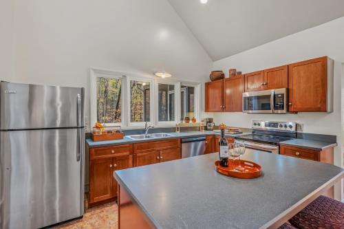 a kitchen with wooden cabinets and a stainless steel refrigerator at Black Forest - Wifi, Pet Friendly, Grill, Deck, Screen Porch, Family Friendly, Fireplace, Pool Access, Hiking in Berkeley Springs