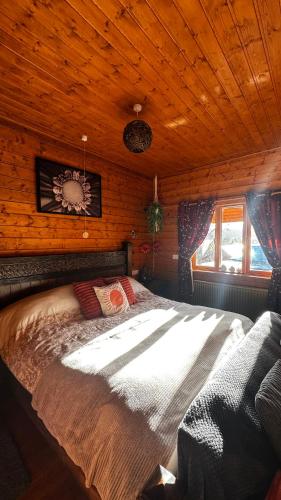a large bed in a room with a wooden ceiling at APPLE Cabin - Little Log Cabin in Wales in Newtown