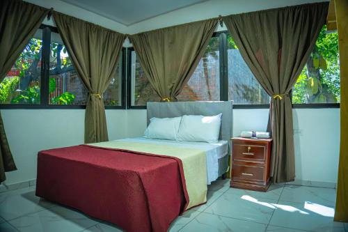 a bedroom with a bed with a red blanket and windows at Hotel D' Palacio Real in San Miguel
