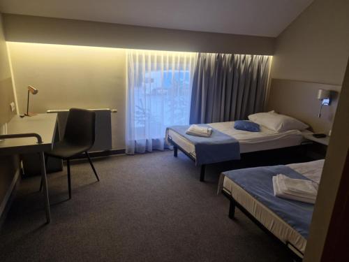 a hotel room with two beds and a desk at Stara Owczarnia NOWA NIEDRZWICA in Nowa Niedrzwica