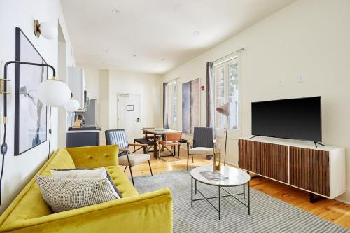 a living room with a yellow couch and a tv at The Louie Hotel New Orleans, Belvilla District 6 Formerly Sonder in New Orleans