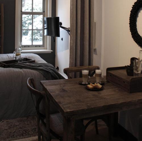 a room with a table and a bed and a table and a table at Het Verborgen Jagershuisje in Wedde