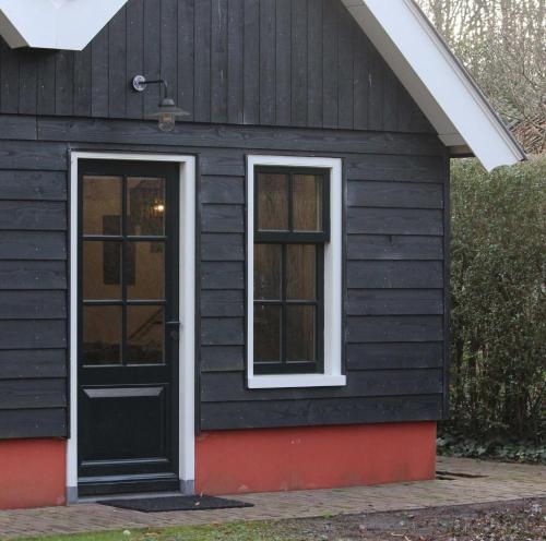 a black house with a black door and windows at Het Verborgen Jagershuisje in Wedde