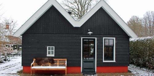 a black house with a cow sitting on a bench at Het Verborgen Jagershuisje in Wedde