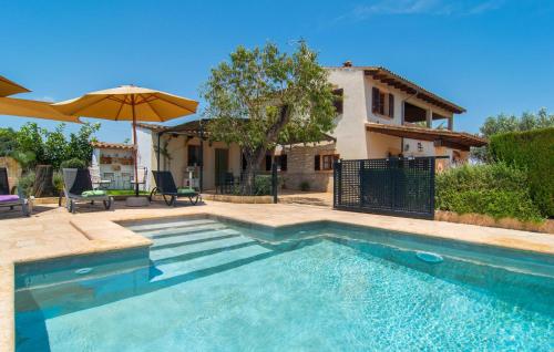 a swimming pool with an umbrella and a house at Es Cipres in Porreres