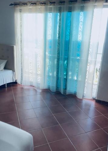 a room with blue and white curtains and a tile floor at Rozana Rooms in Ulcinj