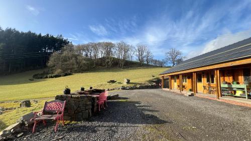 a building with a table and chairs outside of it at Blossom Cabin - Little log Cabin in Wales in Newtown
