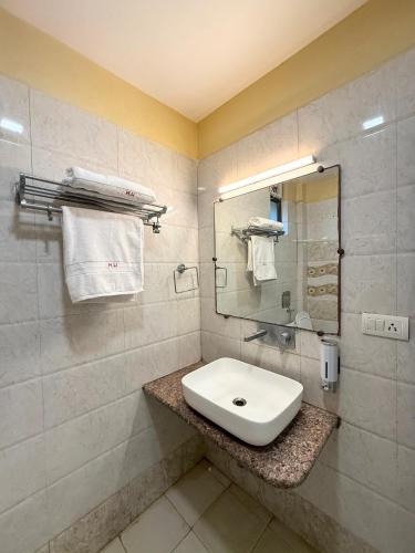 a bathroom with a sink and a mirror and towels at Hotel Wardhman in Jabalpur