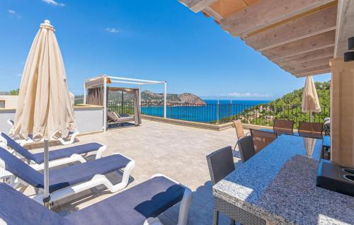a patio with chairs and an umbrella and the ocean at Cap Vermell in Canyamel
