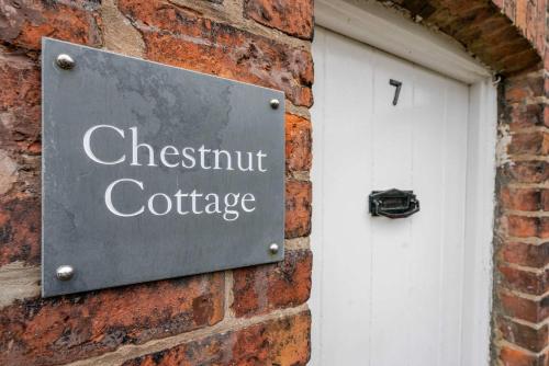a sign on a brick wall next to a white door at The Knutsford Cottage in Knutsford