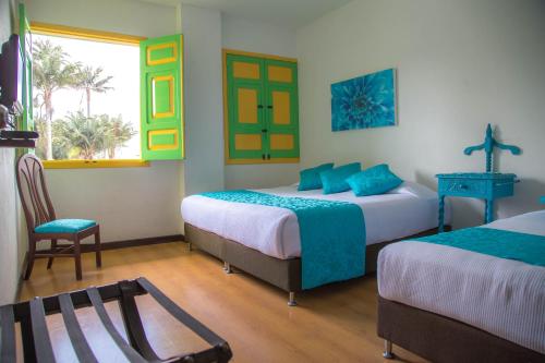 Cette chambre dispose de deux lits, d'une chaise et d'une fenêtre. dans l'établissement La Posada de la Plaza, à Salento