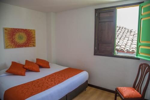 a bedroom with a bed and a window and a chair at La Posada de la Plaza in Salento