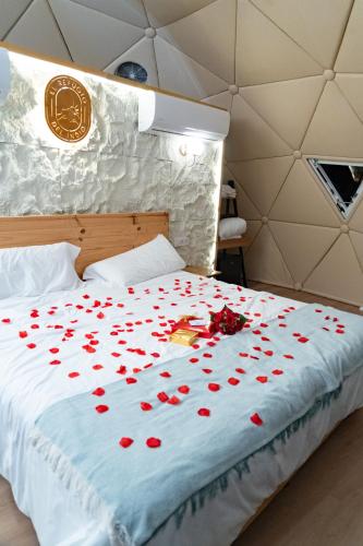 a bed with red rose petals on it at Glamping boutique bajo las estrellas in Archidona