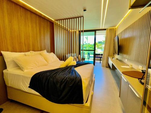a bedroom with a bed and a desk and a television at Flat Lindo em Muro Alto Resort Beach Class Verano Porto de Galinhas in Porto De Galinhas
