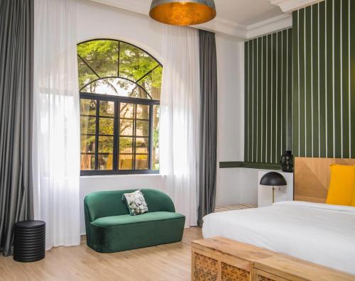 a bedroom with a bed and a green chair at Le Palais d'Akwa in Abidjan