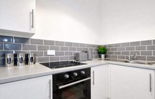 a kitchen with white cabinets and a stove top oven at The Stockton Apartment by GR Estates in Stockton-on-Tees