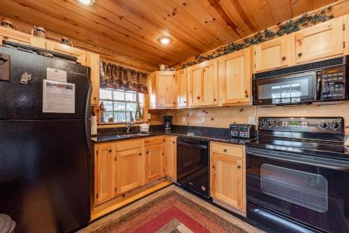 a kitchen with wooden cabinets and black appliances at Tree Haus by Railey Vacations in Oakland