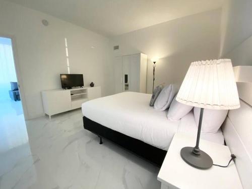 a white bedroom with a bed and a lamp at Zen Vacation Rentals Modern Penthouse Across Ocean in Miami Beach