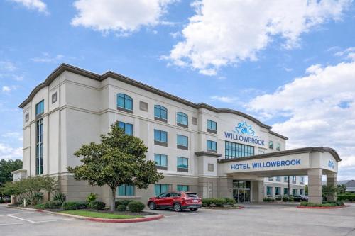 a hotel with a car parked in a parking lot at Hotel Willowbrook in Houston