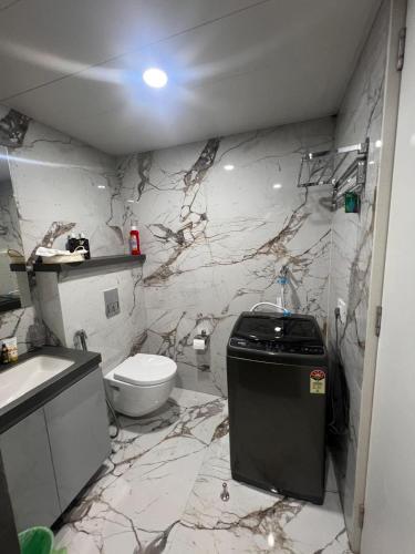 a marble bathroom with a toilet and a sink at NEON - Nirvana Stays With PVT Balcony -1 Km from Airport in Pune