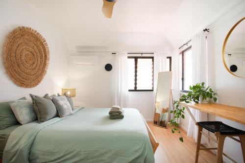 a white bedroom with a bed and a table at Garden Oasis-2br -1 min from the beach & pet friendly! in Suffolk Park
