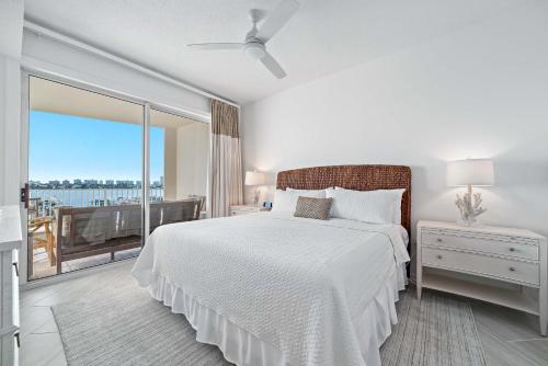 a white bedroom with a bed and a balcony at Harbor Cove 404 in Orange Beach