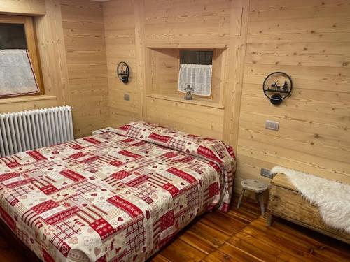 a bedroom with a bed in a room with wooden walls at La casetta di Piera in Brusson