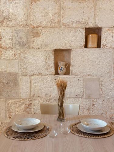 a table with two plates and a vase of grass at Civico 39 in Ostuni