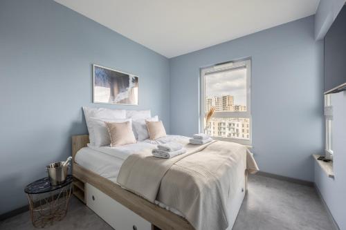 a bedroom with a bed with blue walls and a window at Hygge Amber Aparts - 9th floor in Gdańsk Letnica