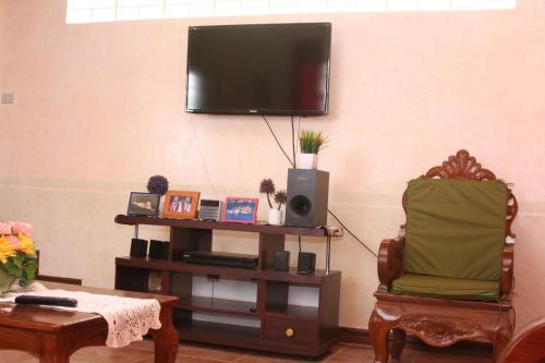 ein Wohnzimmer mit einem Stuhl und einem Flachbild-TV in der Unterkunft Mayoyao View Inn in Banaue