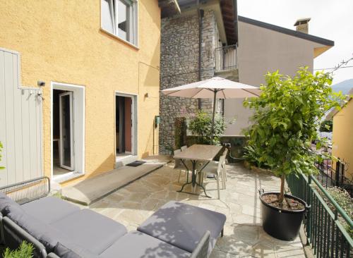 a patio with a table and an umbrella at Milk River - beach front, railway station, lake view in Varenna