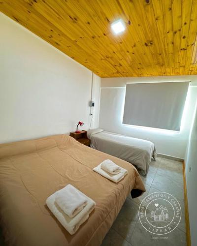 a bedroom with two beds and a wooden ceiling at Lizkar Alojamientos in Esquel