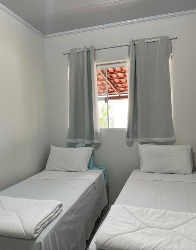 two beds in a room with a window at Raízes do Cerrado in Cavalcante