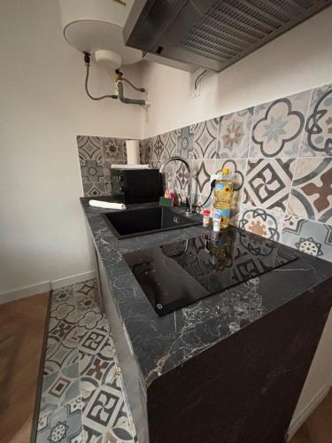 a kitchen with a black counter with a sink at Le Cocon Dijonnais - Cours Cambronne in Dijon