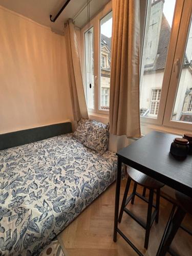 a bed in a room with a table and a window at Le Cocon Dijonnais - Cours Cambronne in Dijon