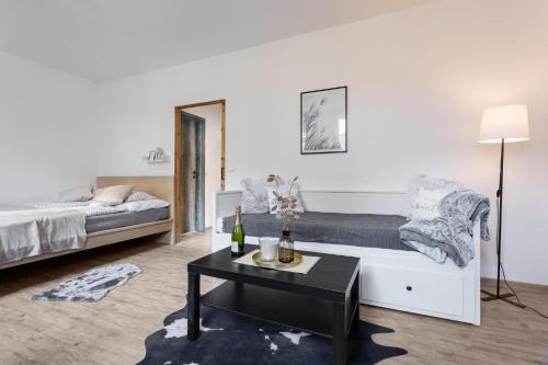 a white bedroom with a bed and a table at V&D apartments by Mountain ways in Rokytnice nad Jizerou