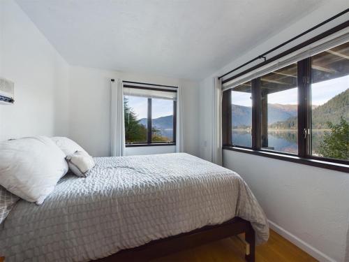 a bedroom with a bed and two windows with mountains at Oceanfront Apartment with Sauna and Covered Deck in Juneau