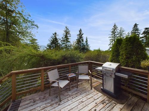 a deck with a grill and a table and chairs at Treetop Retreat w Fire Pit in Juneau