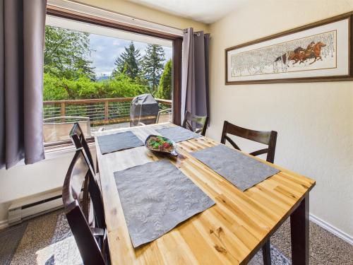 a dining room table with chairs and a large window at Treetop Retreat w Fire Pit in Juneau