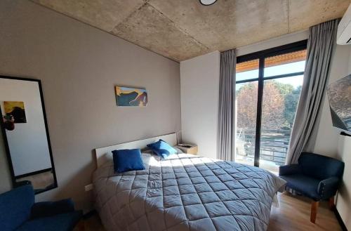 a bedroom with a bed with blue pillows and a window at Departamento - Salta Capital ae - Edificio Usina in Salta