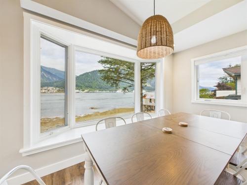 a dining room with a table and two large windows at Oceanfront w Incredible Views in Juneau