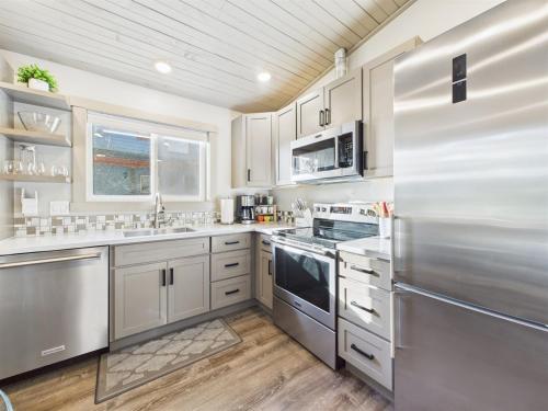 a kitchen with white cabinets and a stainless steel refrigerator at Sunny Point 2BR with Deck & Mountain Views in Juneau
