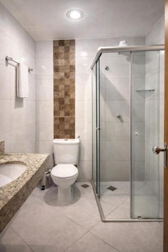 a bathroom with a toilet and a glass shower at Lar Urbano in Manhuaçu